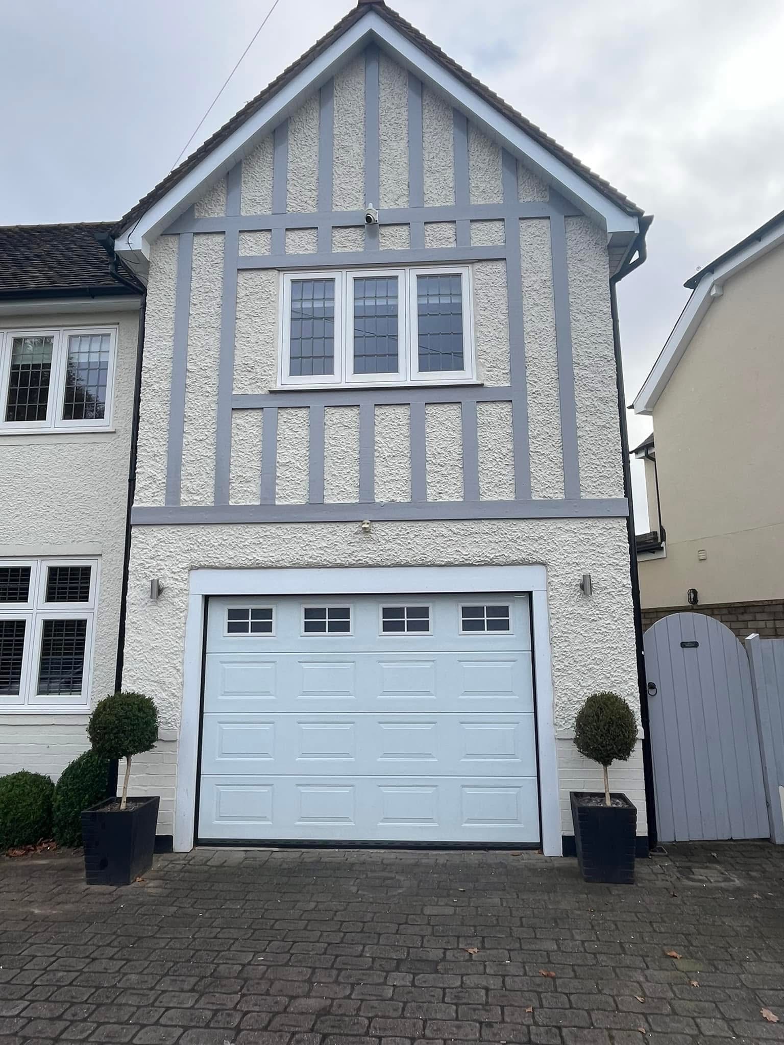 Completed exterior painting project — Tudor-style house with white and grey render finish