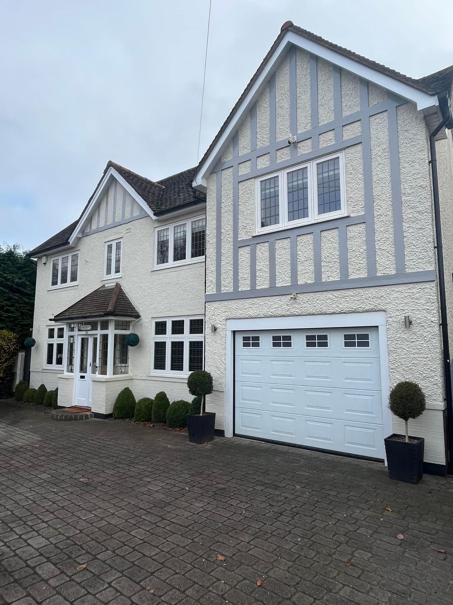 Exterior painting project — large Tudor-style property with garage and bay windows
